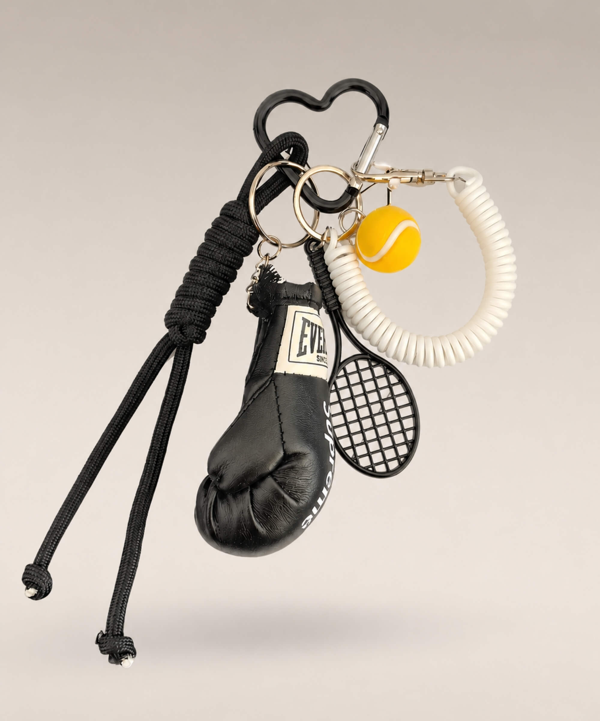 Black boxing glove and tennis rope keychain with white coiled strap and tennis ball charm